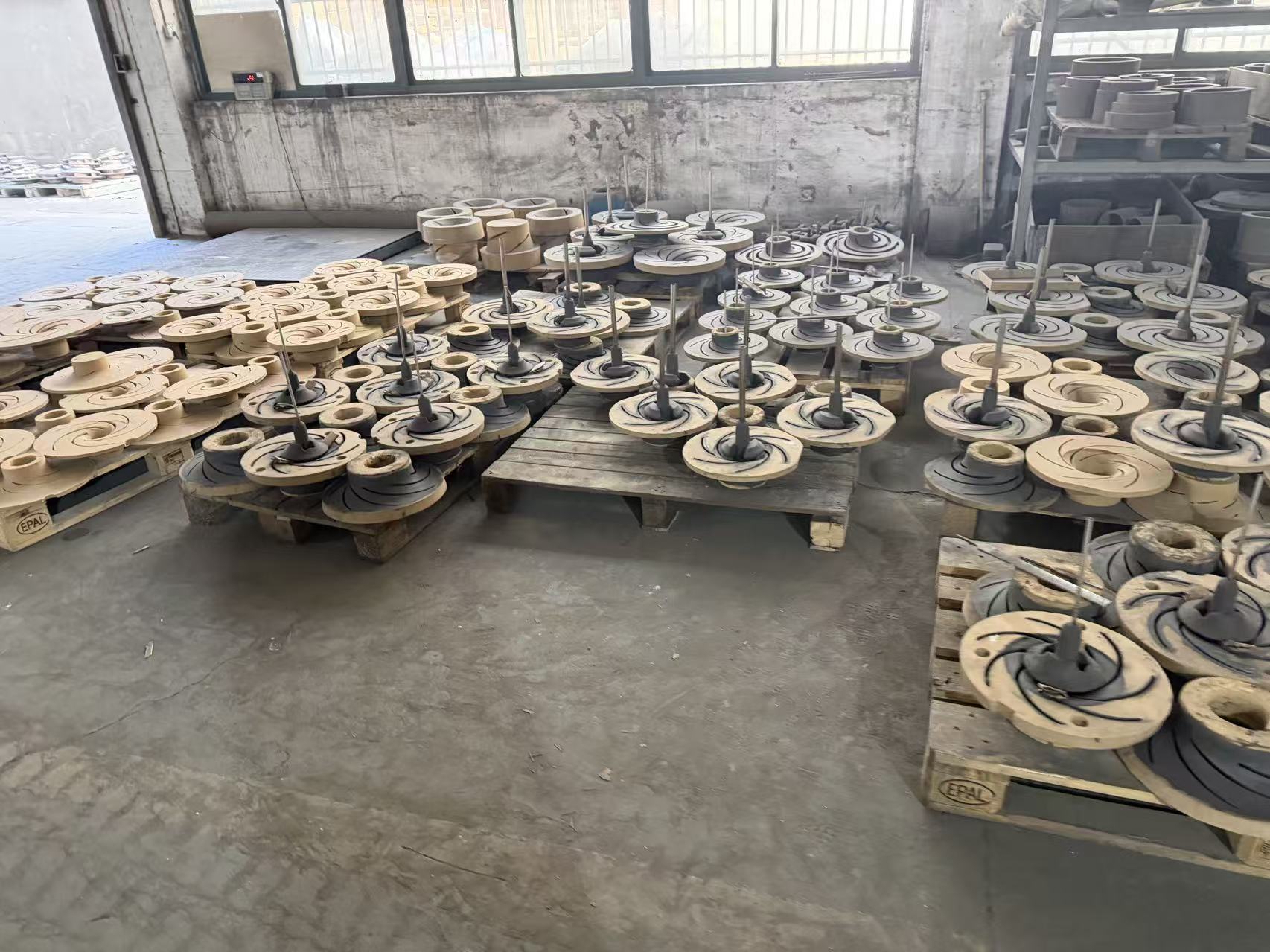 Client-supplied factory photo showing multiple bronze impeller castings in production staging
